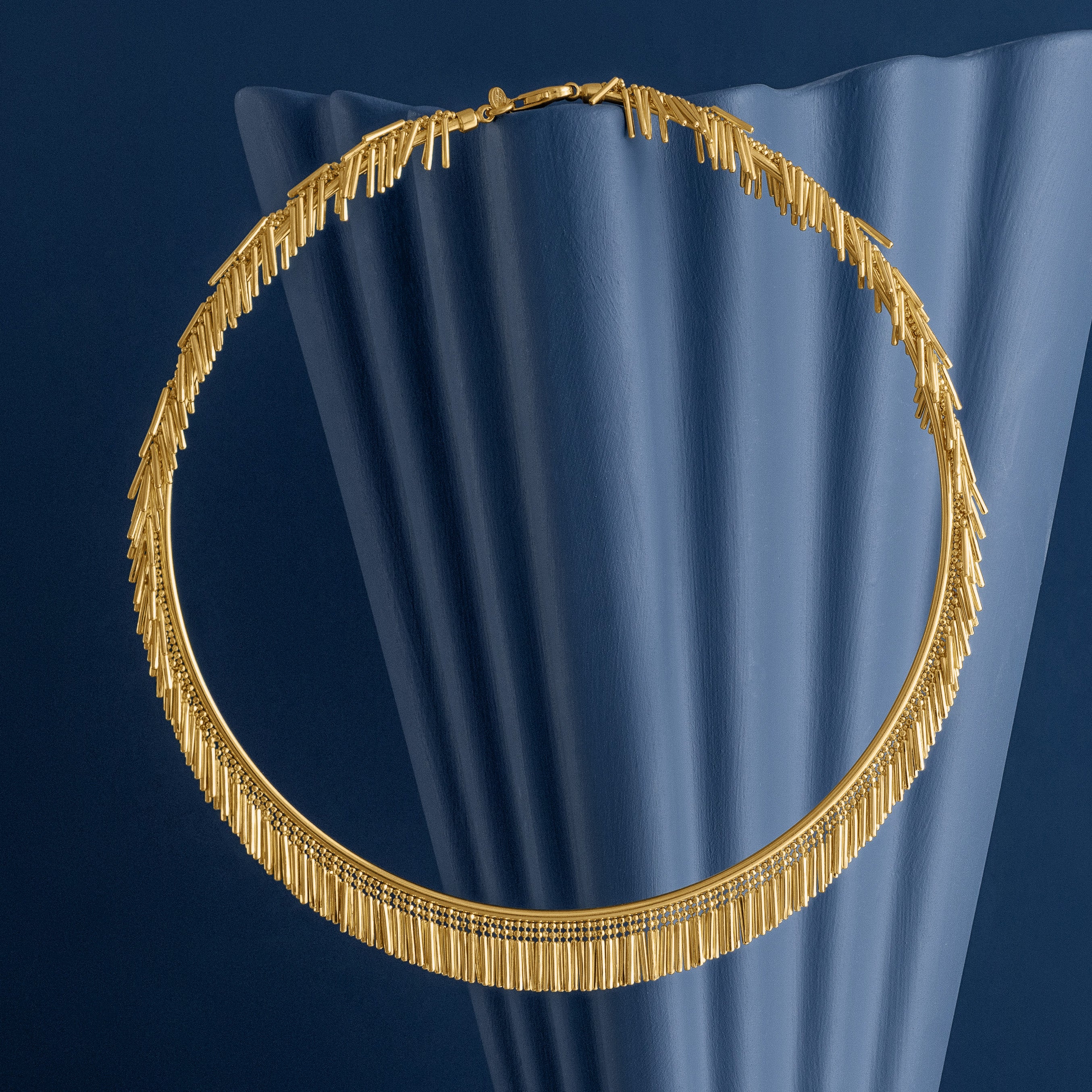 Gold tassel necklace on a blue woven background