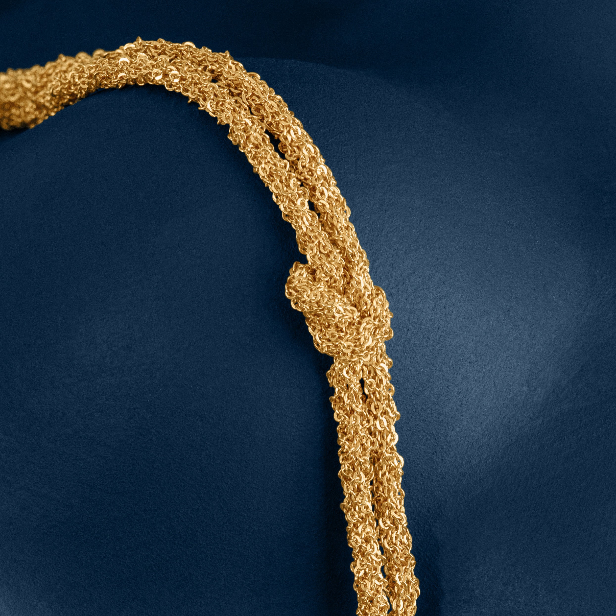 Loel Gold Thread Double Knot Bracelet close up on blue backround
