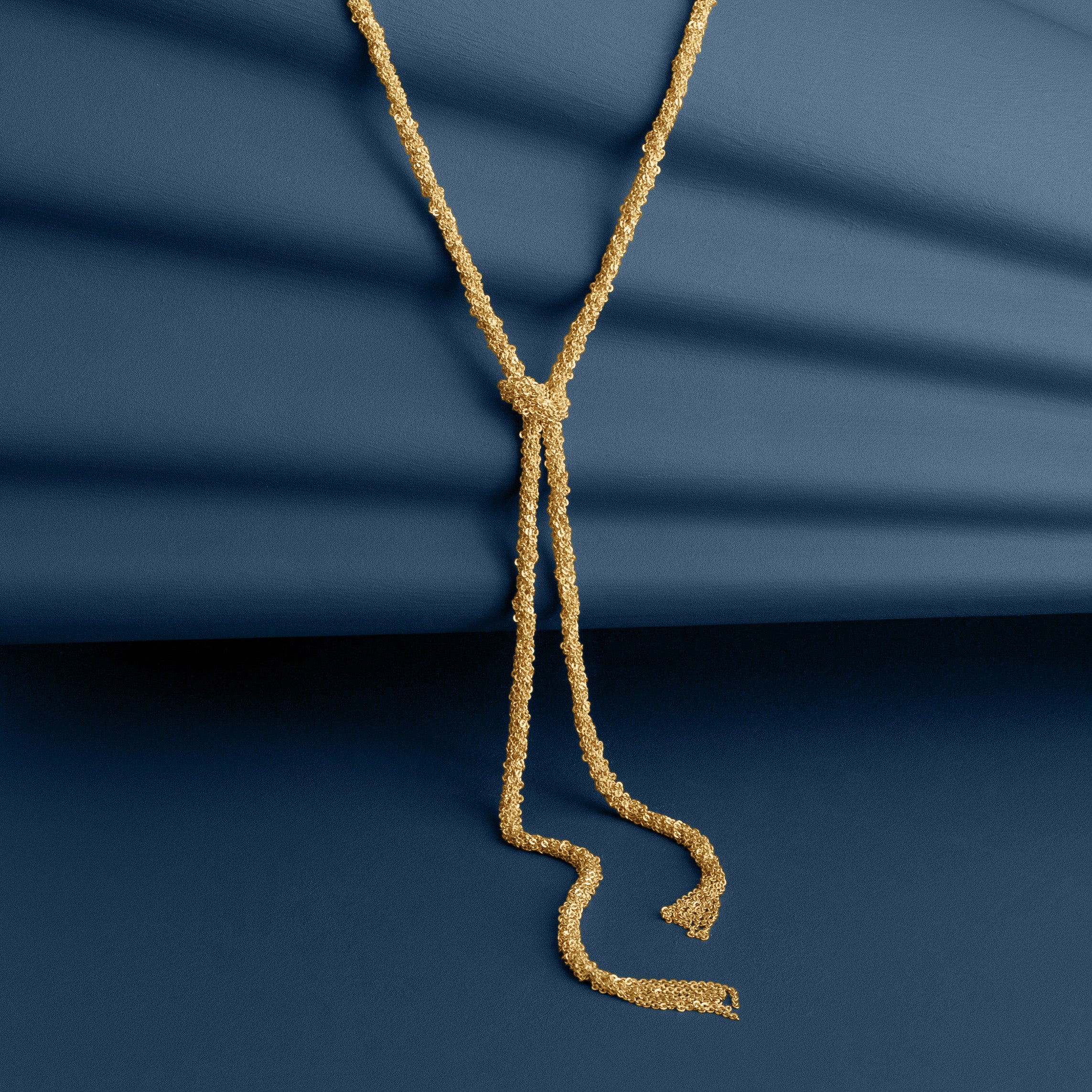 Loel Gold Thread Lariat Necklace on Blue Background