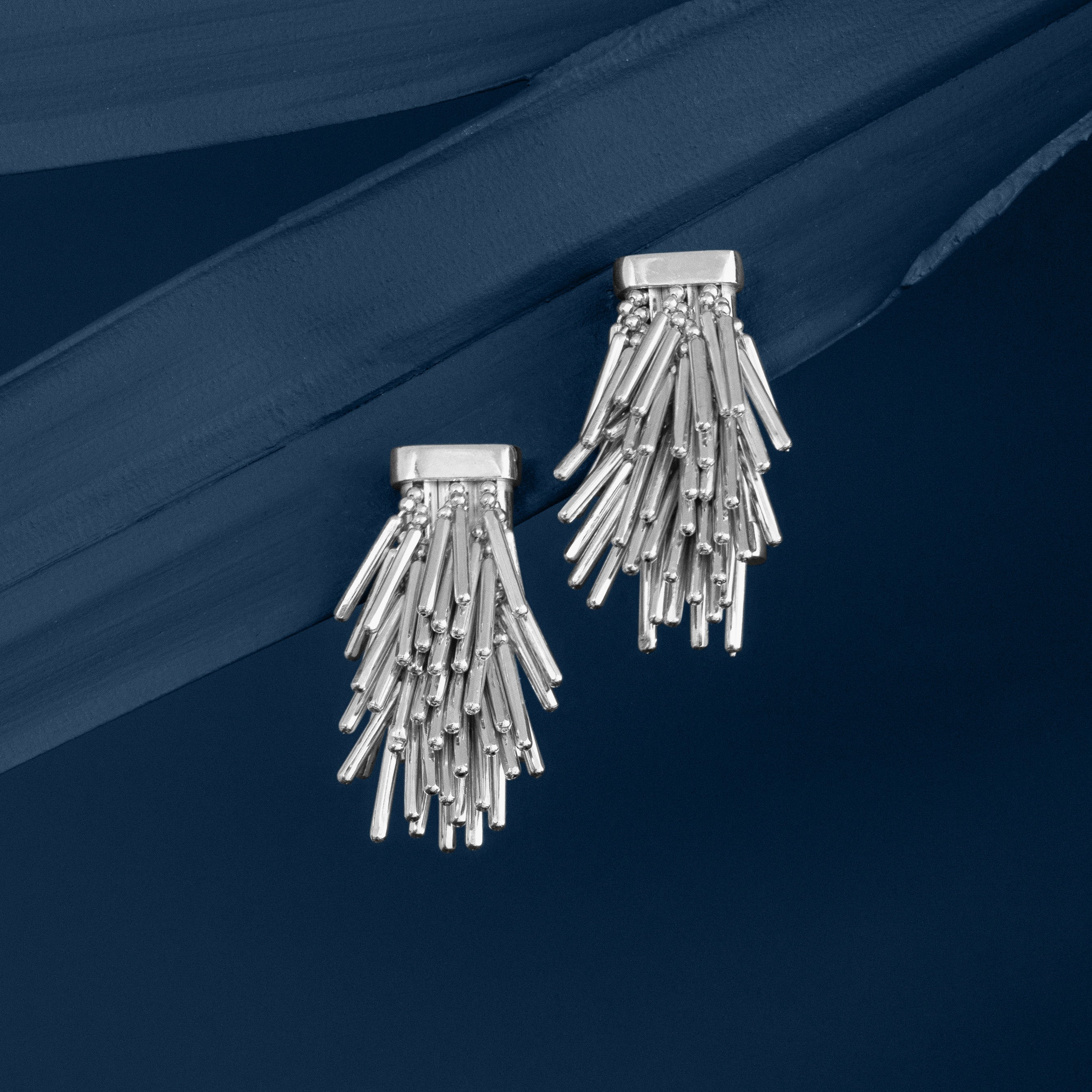 Loel Silver Tassel Drop Earrings on Blue Background