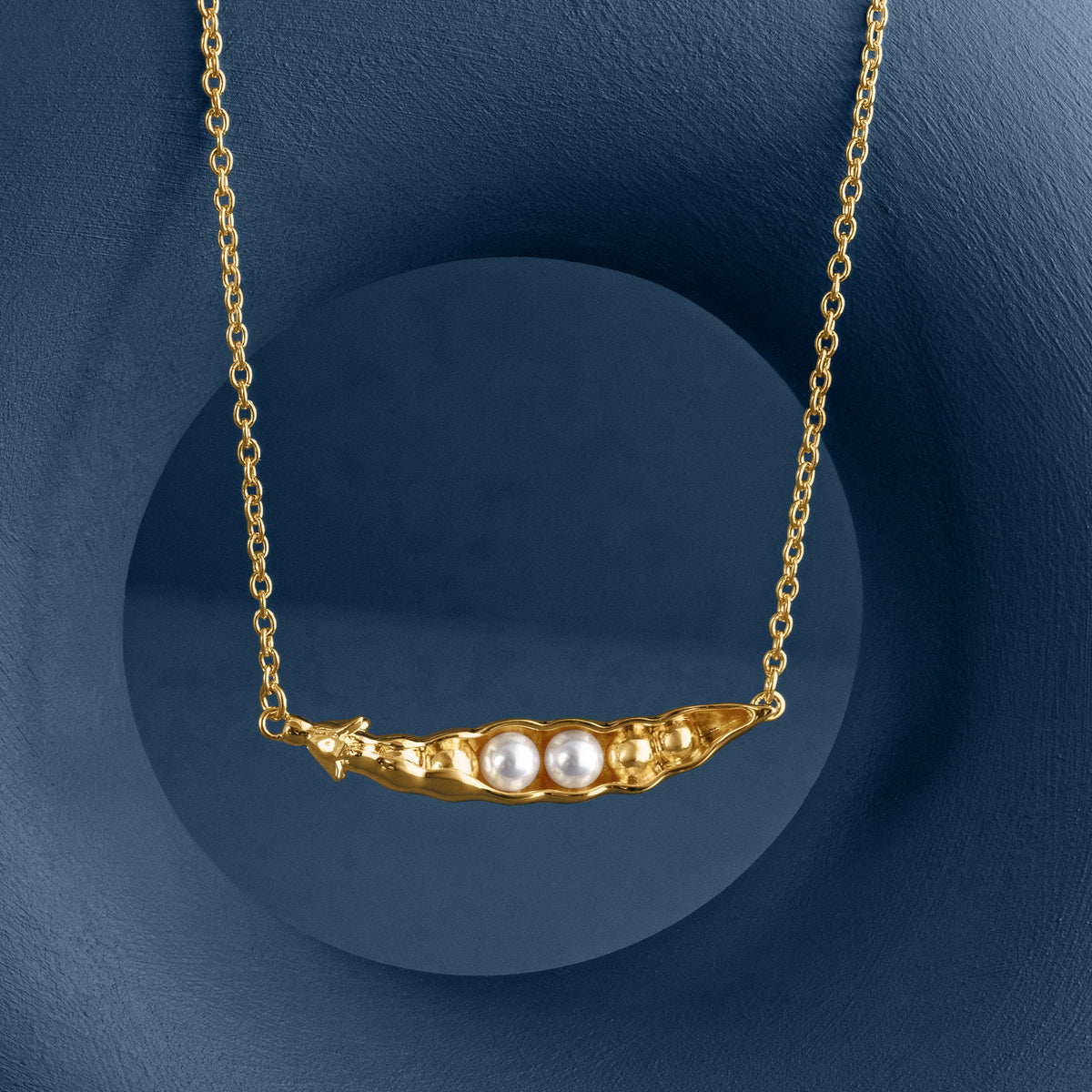 Loel x Minnie Mae Gold Peas in a Pod Pendant hanging on blue v2