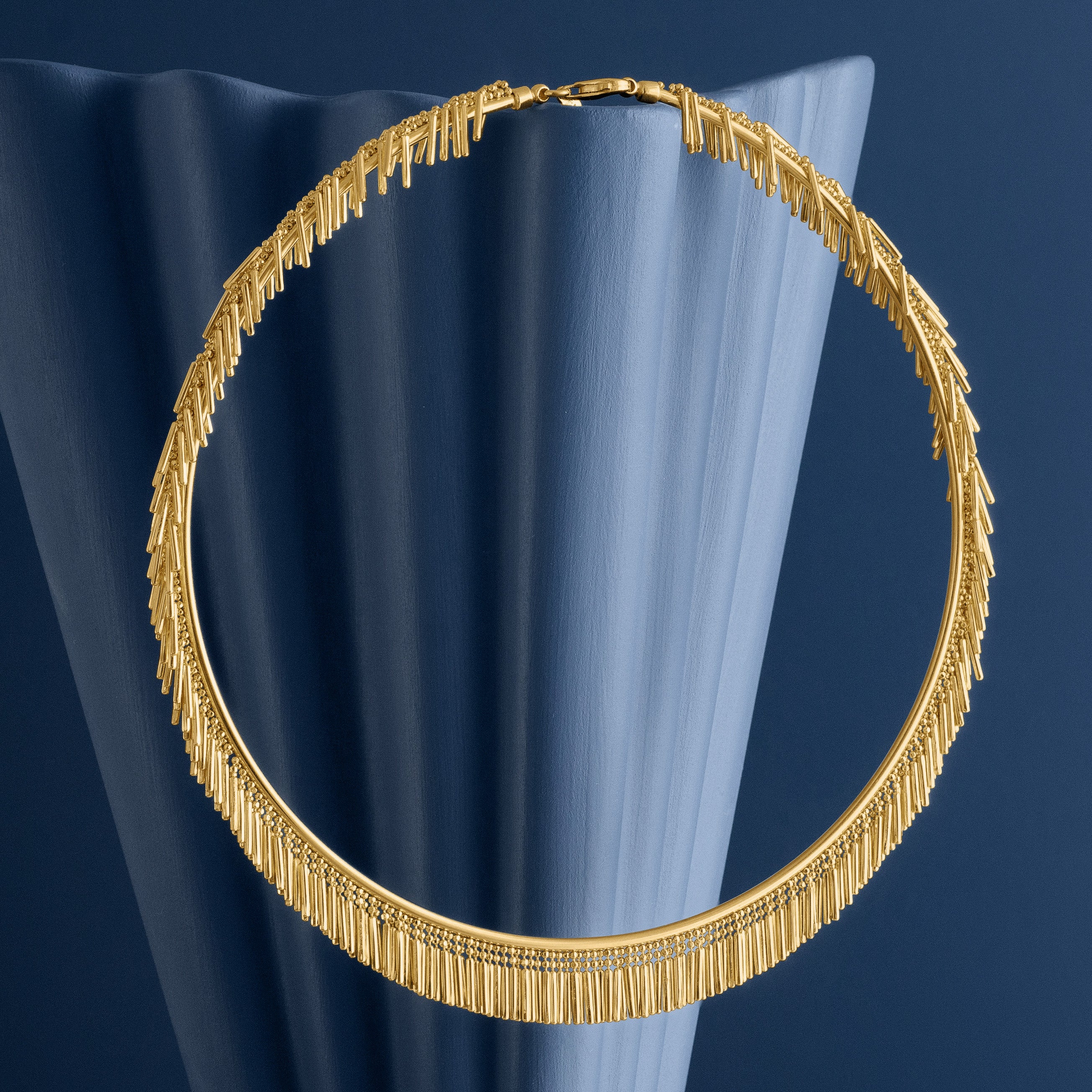 Gold tassel necklace on a blue woven background