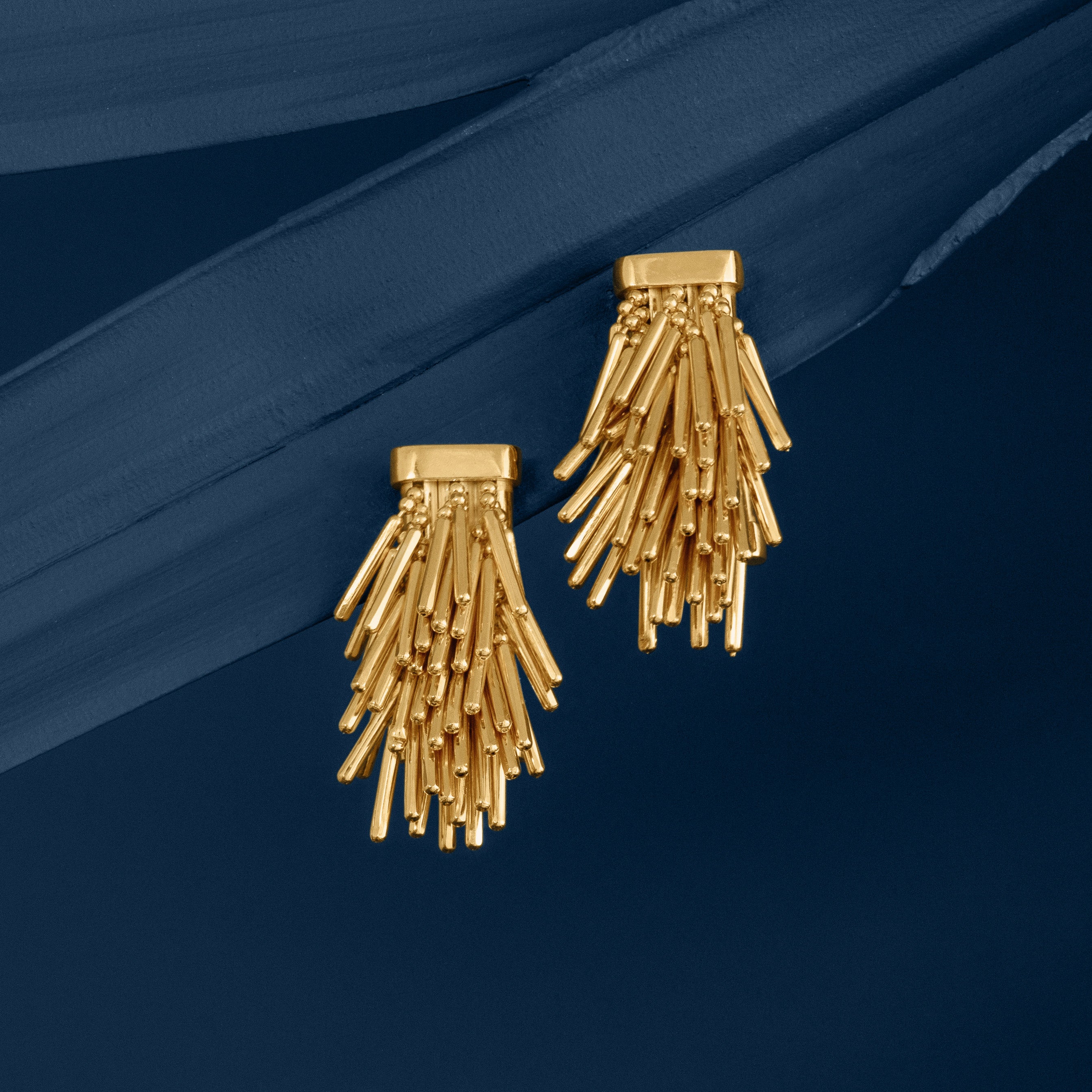 Loel Gold Tassel Drop Earrings on Blue Background