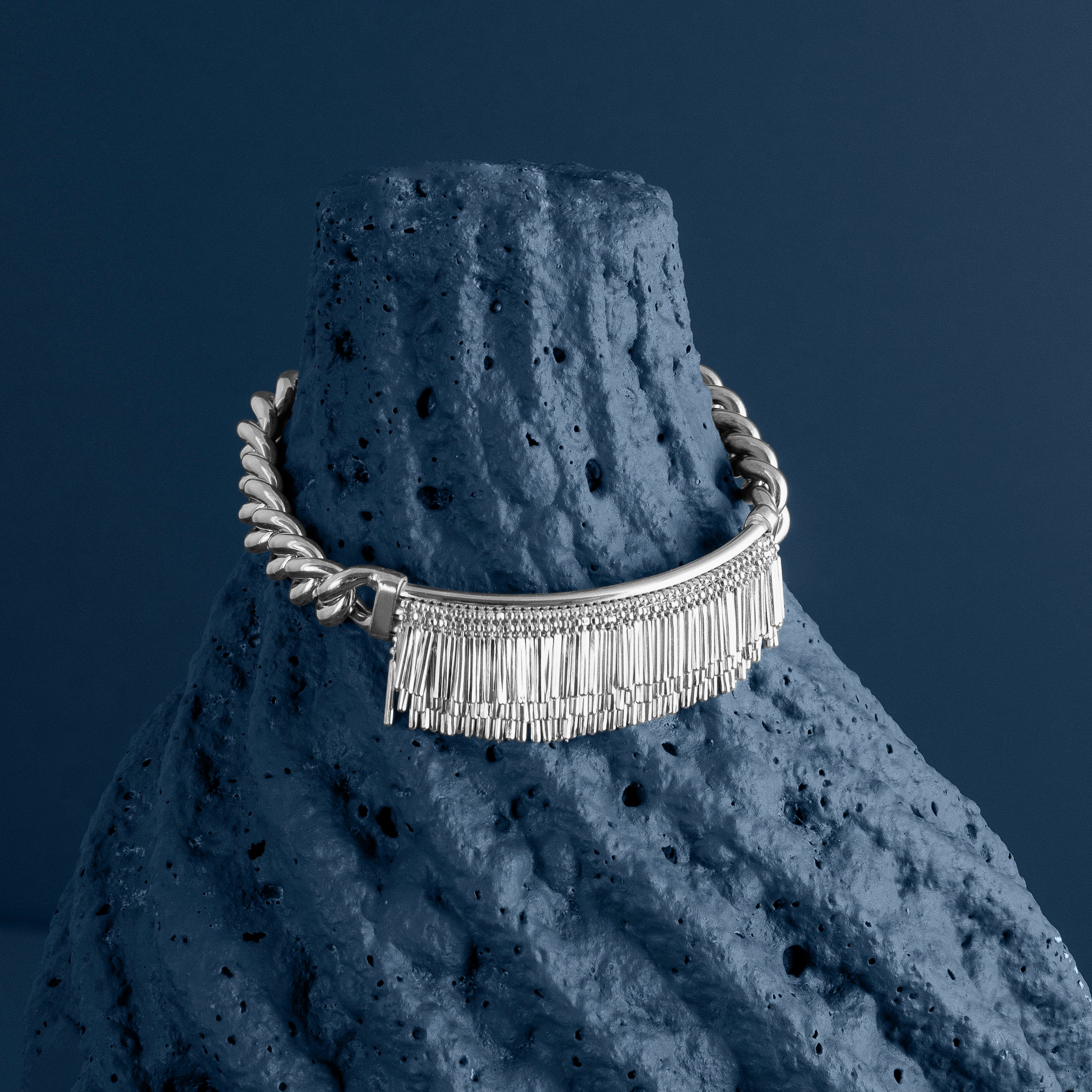 Loel Silver Tassel and Chain bracelet draped on textured stone background