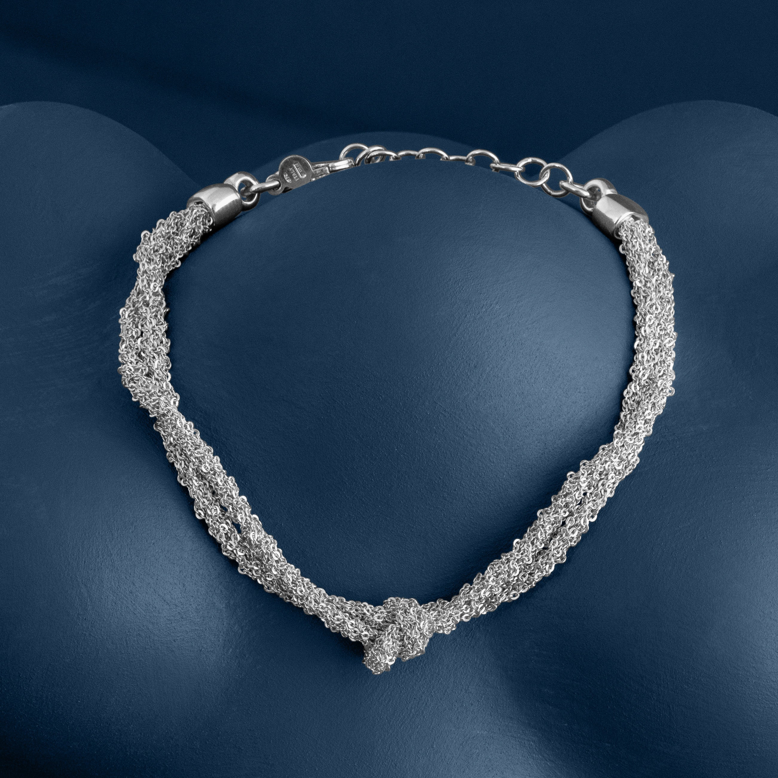 Loel Silver double knot thread bracelet on blue background