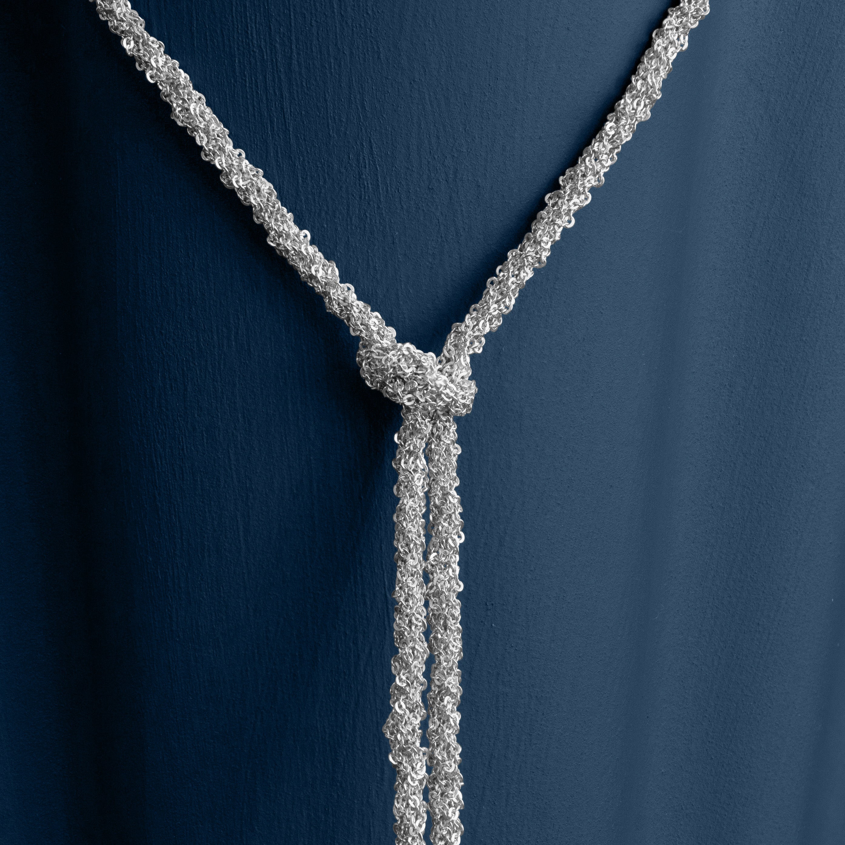 Loel Silver Thread Lariat Necklace close up on blue background
