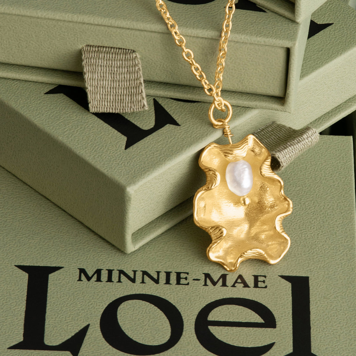 LOEL x Minnie Mae Gold Oyster Shell and Pearl pendant on green boxes