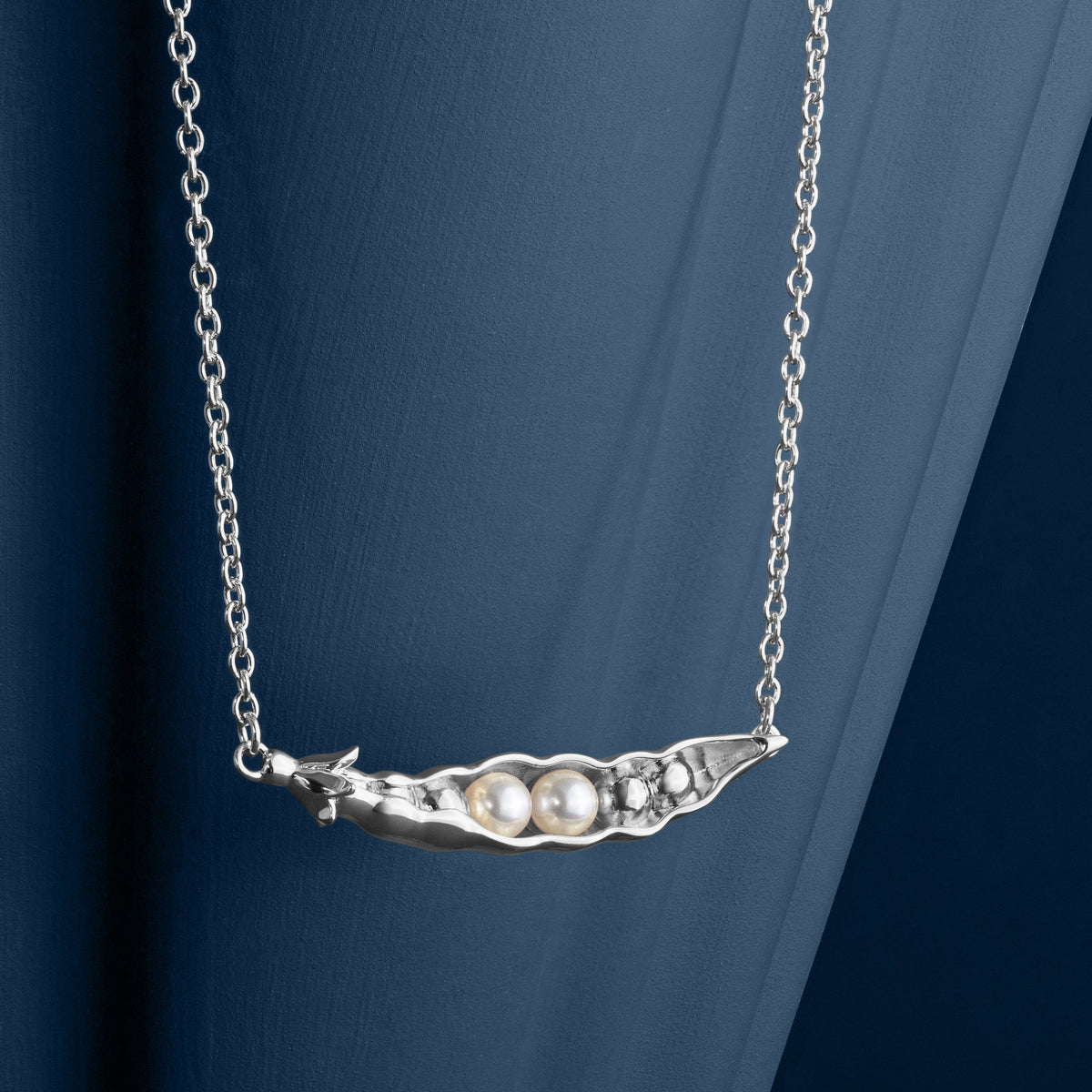 LOEL x Minnie Mae Silver Peas in a Pod Pendant hanging on blue v2