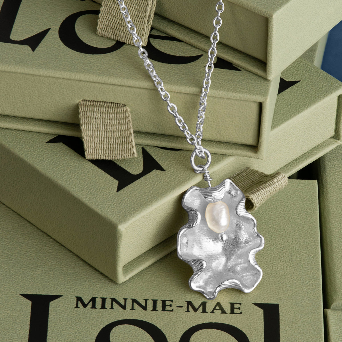 Loel x Minnie Mae Silver Oyster Shell Pendant on green boxes